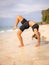 Beach yoga. Young woman practicing Eka Pada Chakrasana, One Legged Wheel Pose. Upward facing bow pose is a deep backbend.