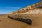 A beached carcass of a shipwreck on Old Hunstanton Beach beneath the white, red and orange stratified cliffs in Norfolk, UK