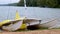 A beached catamaran sailboat rests partly in water on the shore of a lake