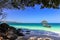 Beaches of small islands, clear water The turquoise has trees, large stones and a boat floating in the water.