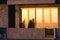 Beachgoers reflections at windows of a  beach house brightly lid by sunset