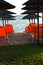 Beachscape with orange chairs, thatched sunshades and island in a background