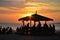 beachside eatery, with view of sunset over the ocean, and silhouettes of people on the sand