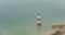 Beachy head lighthouse at the edge of white chalk cliff. Safety warning in the ocean