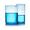 Beakers with liquid on table against color background