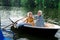 Beaming aged woman wearing yellow shit sitting in boat with husband