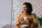 Beaming dark-eyed woman looking at window while drinking some coffee