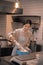 Beaming dark-haired worker of little cafeteria cooking in the kitchen