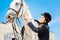 Beaming female rider taking care of her brown racehorse