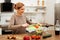 Beaming light-haired woman staying in kitchen and preparing light meal