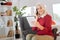 Beaming retired woman talking on phone and using digital tablet