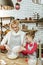 Beaming short-haired woman mixing dough while daughter helping