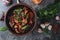 Bean soup with herbs in a clay bowl with fresh rye bread and garlic on a slate table