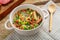 Bean soup with smoked meats and greens of Jewish cuisine cholit in a tureen and a wooden spoon.