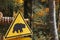 Bear caution yellow sign at autumn forest background. Wild animal danger concept