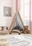 bear next to tent with cushions in kid`s room interior with poster, rug and pouf. Real photo