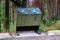 A bear proof garbage container along side a parking lot