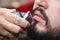 Beard styling and cut. Close up cropped photo of a styling of a red beard. Advertising and barber shop concept.