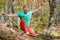 A bearded aged man sits on a slackline balancing in meditation. Professional tightrope walker in the autumn forest