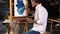 Bearded artist sitting in front of easel and painting