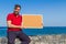 Bearded attractive inviting young man holding a framed blank corkboard in blue sky