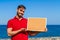 Bearded attractive inviting young man holding a framed blank corkboard in blue sky