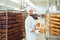 Bearded baker smiles holding a basket of bread at the bakehouse