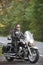 Bearded biker in black leather jacket on modern motorcycle on country roadside.