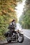 Bearded biker in black leather jacket on modern motorcycle on country roadside.