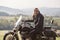 Bearded biker with long hair in black leather jacket and sunglasses sitting on modern motorcycle.