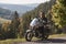 Bearded biker with long hair in black leather jacket and sunglasses sitting on modern motorcycle.