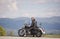 Bearded biker with long hair in black leather jacket and sunglasses sitting on modern motorcycle.