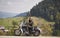 Bearded biker with long hair in black leather jacket and sunglasses sitting on modern motorcycle.