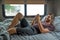 A bearded brown haired hypster man wearing a red t-shirt lays down laughing relaxing on his bed in his camper talking to someone