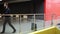 Bearded brunette man is looking at his watch and going away leaving his suitcase near glass fence in modern building