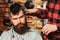 Bearded brutal hipster getting hairstyle. Male hairstylist serving client. Barber making haircut using machine and comb. New