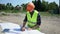 Bearded builder engineer in orange helmet analysing drawing. Preparation for construction