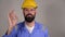 Bearded builder in helmet showing ok gesture ,concept of success and approval over grey background