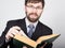 Bearded businessman in a business suit and tie, reading a thick book