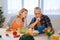 Bearded businessman sitting near his wife cooking breakfast