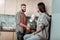 Bearded caring man cutting salad standing near wife drinking tea