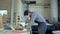 Bearded carpenter working with electric planer on wooden plank in workshop.