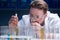 Bearded chemist in goggles with reagents in tubes in laboratory