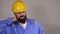 Bearded constructor or builder or foreman or repairman in the yellow building helmet suffering neck pain
