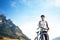 bearded cyclist stands with a bicycle against a background of blue sky and mountains. cycling and health-related hobbies