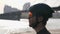 Bearded cyclist wearing black helmet and sunglasses looking focused towards horizon. River and bridge in the background. Cycling c