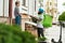 Bearded delivery man in helmet with thermo backpack giving away pizza to a female customer, while delivering food