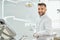 Bearded dentist in white uniform sitting in dental office