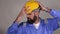 Bearded engineer touch  safety helmet with hands on grey background