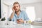 Bearded fair-haired male office worker looking unhappily at screen of smartphone, leaning on his elbow, sitting at table